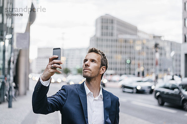 Deutschland  Berlin  Geschäftsmann beim Fotografieren mit dem Smartphone