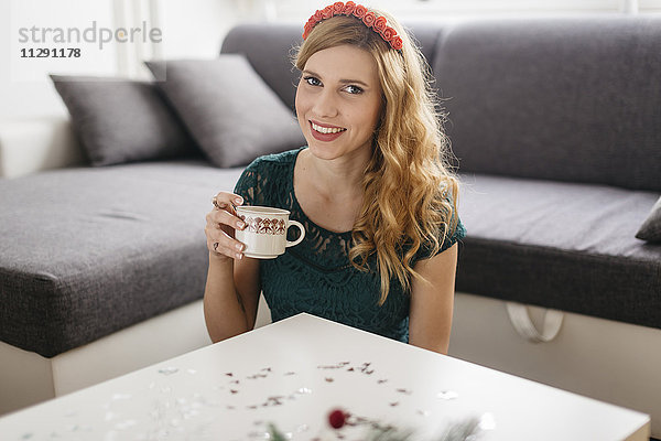 Porträt einer lächelnden jungen Frau  die zu Hause zu Weihnachten Kaffee trinkt.