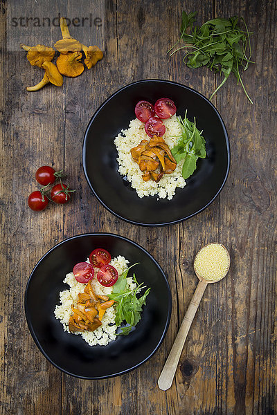 Schale mit Couscous-Salat mit Tomaten  Rucola und Pfifferlingen auf Holz