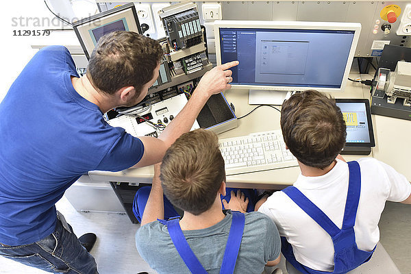 Technischer Lehrer  der die Schüler am Computerbildschirm unterrichtet.