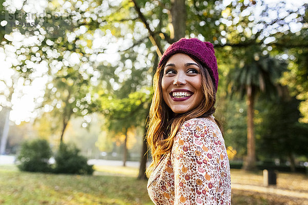 Glückliche junge Frau mit Wollmütze in einem Park im Herbst