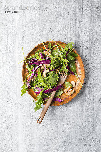 Salat mit Rotkohl  Rucola  Einkorn und verschiedenen Nüssen auf Holzplatte