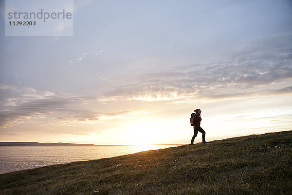 Island  Frau beim Wandern auf einem Hügel in der Dämmerung