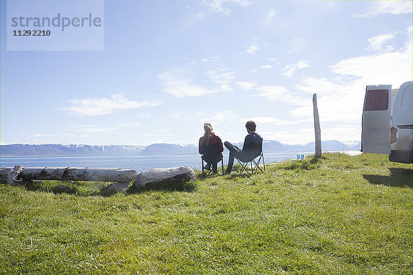 Island  Rückansicht des auf Campingstühlen sitzenden Paares mit Blick auf die Aussicht
