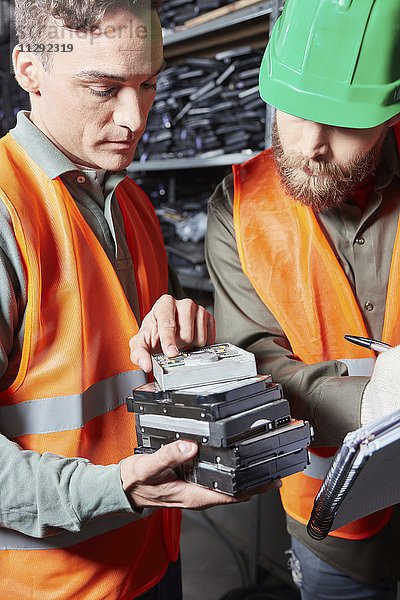 Arbeiter in der Computer-Recycling-Anlage notieren Seriennummer der Festplatte