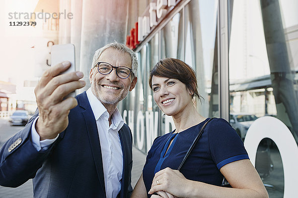 Geschäftsmann und Geschäftsfrau mit einem Selfie im Freien