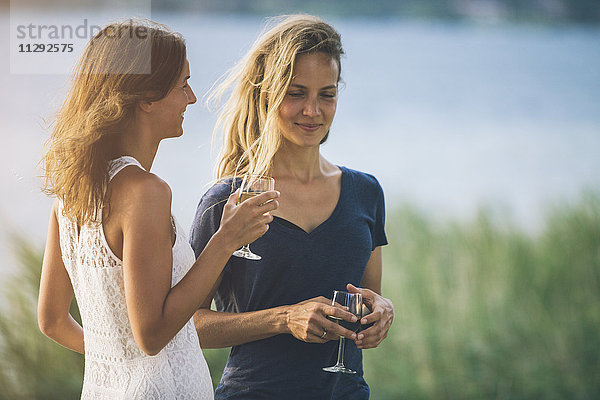 Italien  Gardasee  zwei junge Frauen am Seeufer bei einem Glas Wein