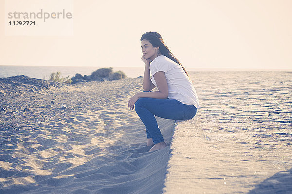 Junge Frau am Strand sitzend