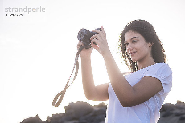 Junge Frau am Strand beim Fotografieren