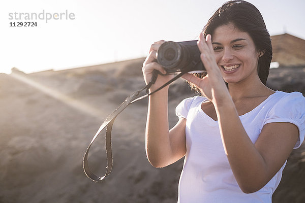 Junge Frau am Strand beim Fotografieren