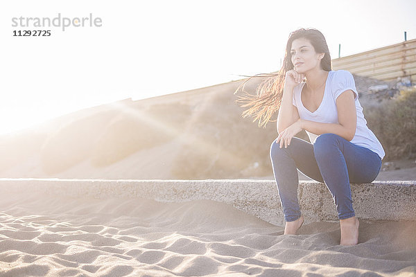 Junge Frau am Strand sitzend