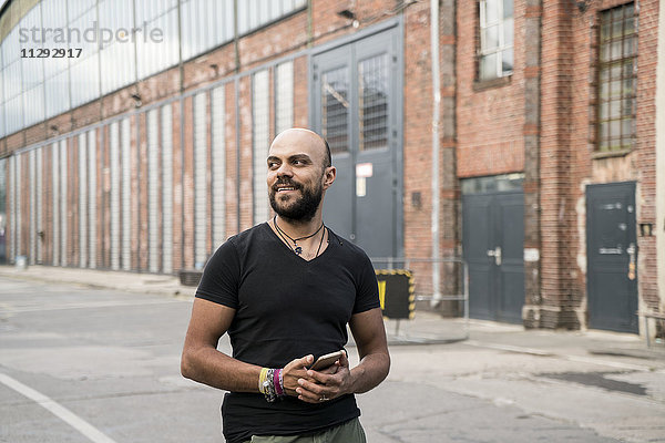 Porträt eines lächelnden Mannes mit Smartphone