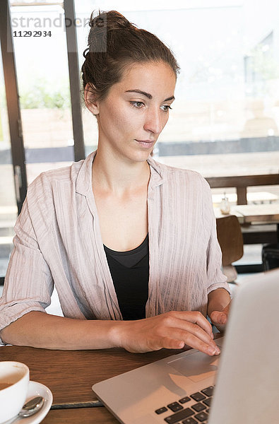 Junge Frau arbeitet mit Laptop in einem Coffee-Shop