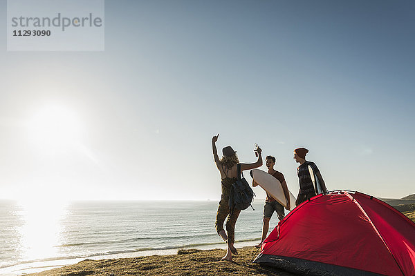 Drei Freunde mit Surfbrettern beim Camping am Meer