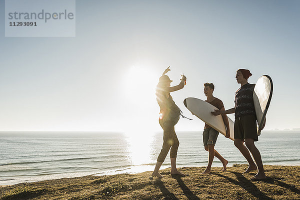 Drei Freunde mit Surfbrettern beim Camping am Meer