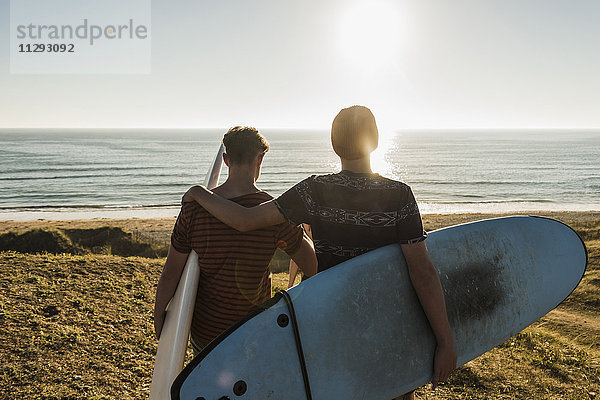Rückansicht von zwei besten Freunden mit Surfbrettern am Meer