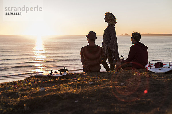 Drei Freunde genießen den Sonnenuntergang am Strand