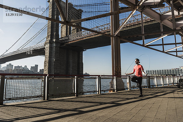 USA  New York City  Mann springt am East River unter der Brooklyn Bridge.