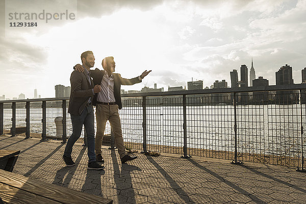 USA  New York City  zwei Geschäftsleute  die gemeinsam am East River entlang gehen.