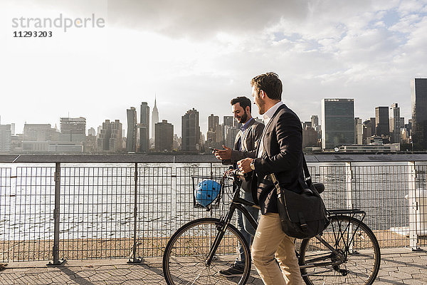 USA  New York City  zwei Geschäftsleute mit Fahrrad entlang des East River