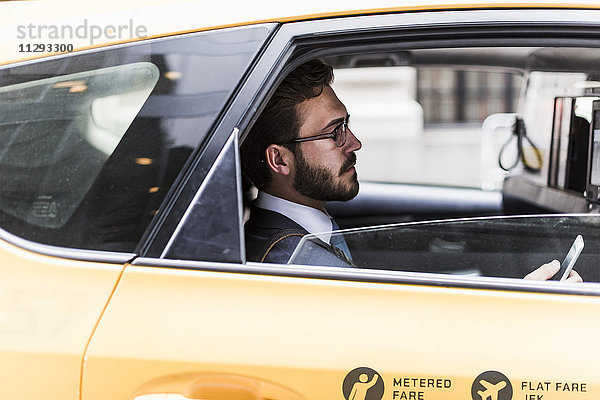 USA  New York City  Geschäftsmann mit Handy im Taxi