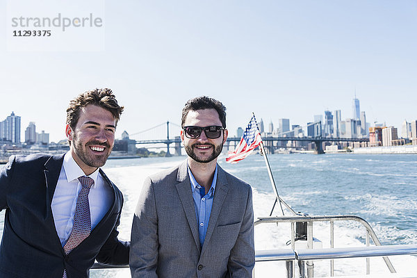 USA  New York City  zwei lächelnde Geschäftsleute auf der Fähre auf dem East River