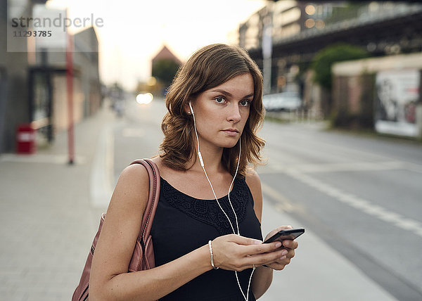 Deutschland  Junge Frau mit Smartphone erkundet Hamburg