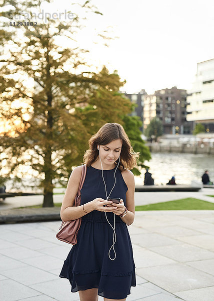 Deutschland  Junge Frau mit Smartphone erkundet Hamburg