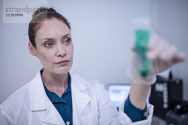 Frau hält Reagenzglas im Labor