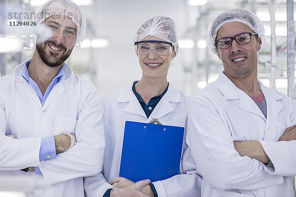 Porträt von drei lächelnden Wissenschaftlern in Schutzkleidung