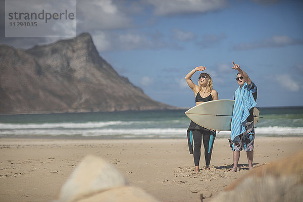 Teenager Junge mit Down-Syndrom und Frau mit Surfbrett am Strand