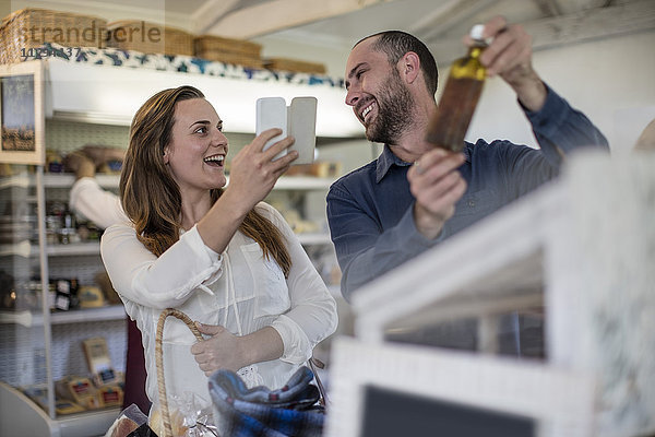 Glückliches Paar beim Fotografieren mit dem Smartphone im Hofladen