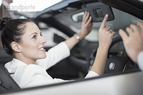 Lächelnde Frau sitzt im Auto beim Autohaus