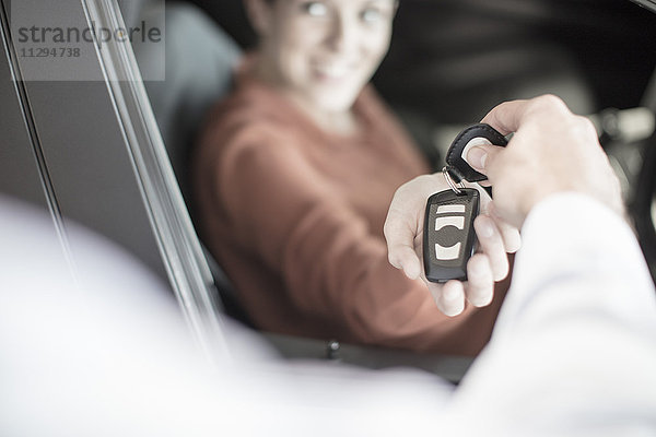 Autohändler übergibt Schlüssel an Frau im Autohaus