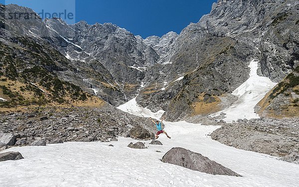 Junger Mann springt  Schneefeld vor der Ostwand des Watzmann  Berchtesgadener Land  Oberbayern  Bayern  Deutschland  Europa