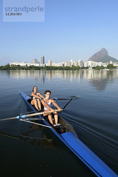 Zwei junge Frauen beim Rudertraining früh Morgens in der Lagune Lagoa Rodrigo de Freitas  Stadtteil Lagoa  hinten Skyline mit Zuckerhut  Rio de Janeiro  Brasilien  Südamerika