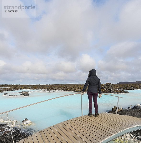 Touristin steht auf einer Holzbrücke  Blaue Lagune bei Grindavik  Südwestisland  Island  Europa