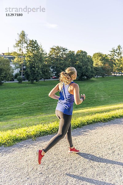 Junge Frau in Sportkleidung joggt in einem Park  München  Oberbayern  Bayern  Deutschland  Europa