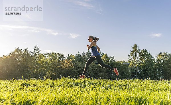 Junge Frau in Sportklamotten joggt in einem Park  München  Oberbayern  Bayern  Deutschland  Europa