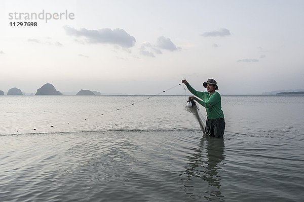 Fischer steht im Wasser und fischt mit Netz  Tubkaek Beach  Krabi  Thailand  Asien