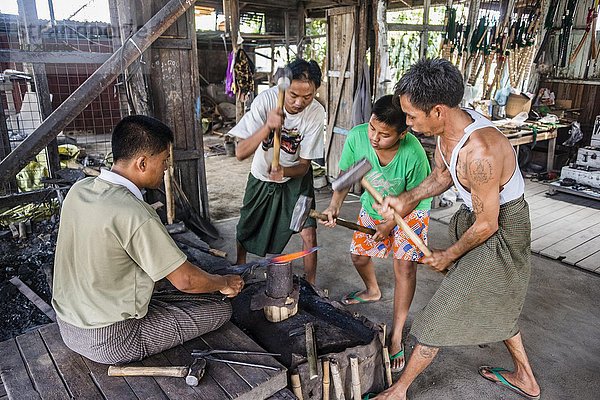 Einheimische hämmern mit Hammern auf glühendes Metallstück  Schmied  Schmiede  Inle Lake  Inle See  Shan Staat  Myanmar  Asien