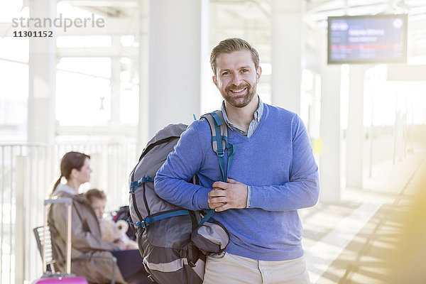 Portrait lächelnder Mann mit Rucksack am Flughafen