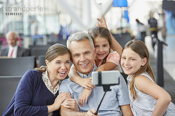 Familie nimmt Selfie mit Selfie-Stick am Flughafen mit