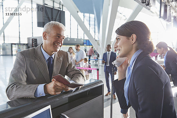 Kundendienstmitarbeiter hilft Geschäftsmann mit Pass am Flughafen-Check-in-Schalter