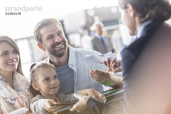 Kundenbetreuerin hilft der Familie mit Tickets am Flughafen-Check-in-Schalter