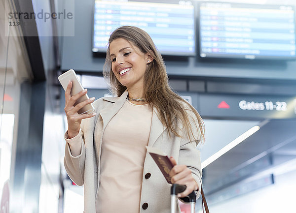 Geschäftsfrau mit Reisepass mit Handy am Flughafen