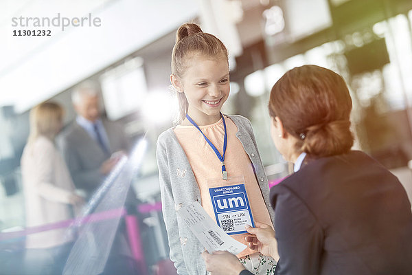 Flugbegleiterin im Gespräch mit Mädchen am Flughafen