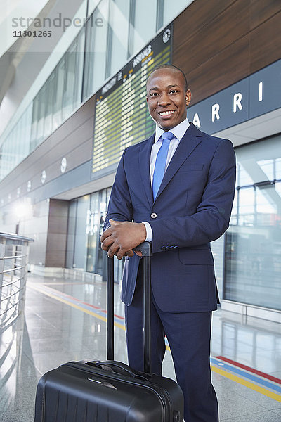 Porträt selbstbewusster Geschäftsmann mit Koffer in der Flughafenhalle