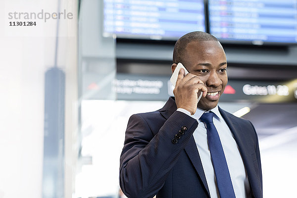 Geschäftsmann beim Telefonieren am Flughafen