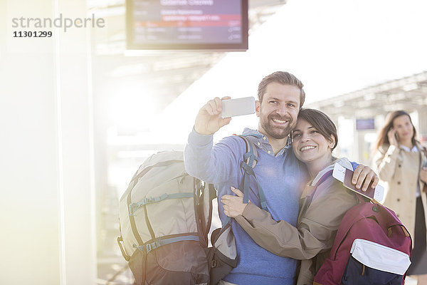 Paar mit Rucksäcken  die Selfie am Bahnhof mitnehmen